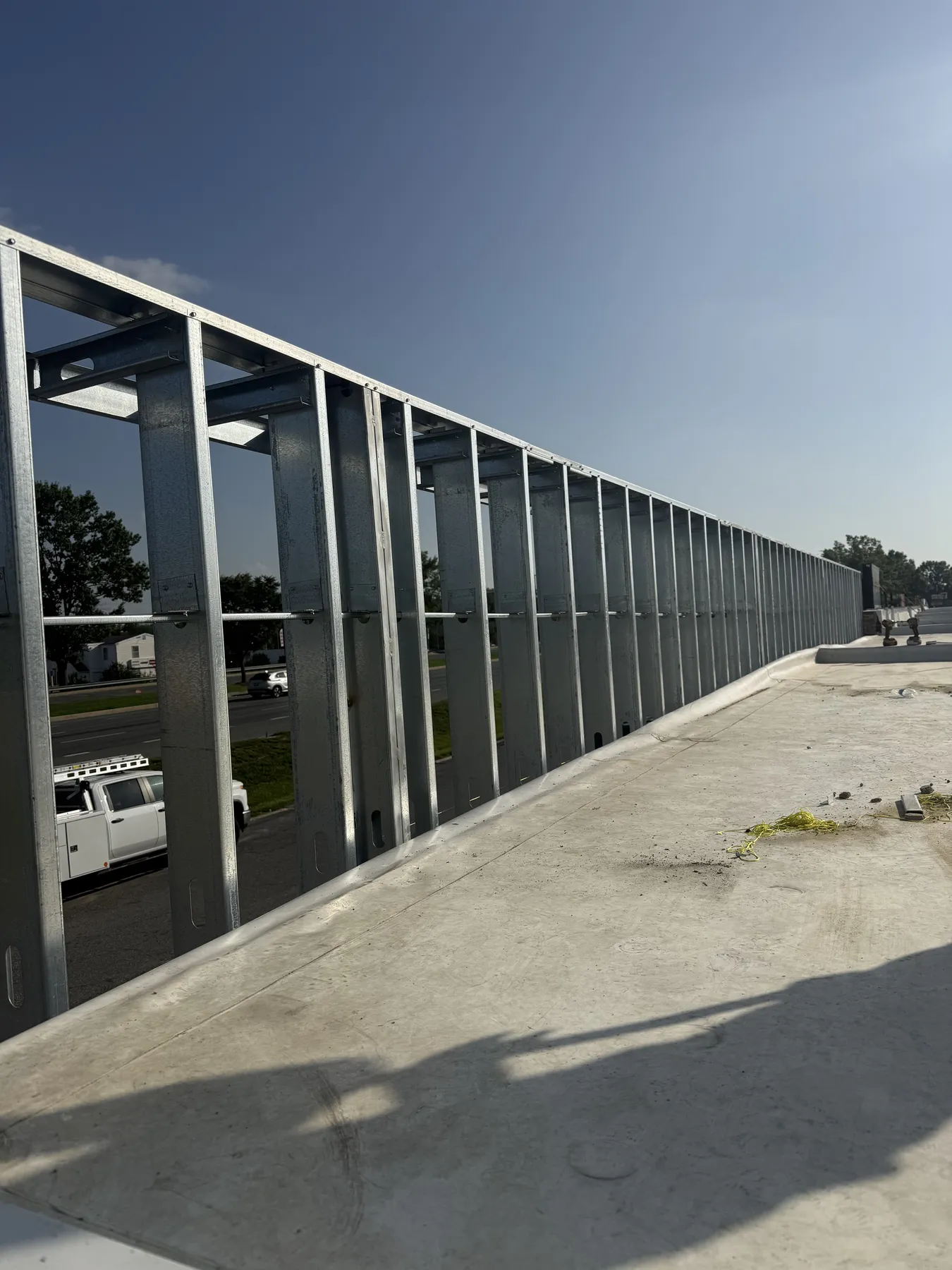Long commercial metal stud framing run beside a parking area